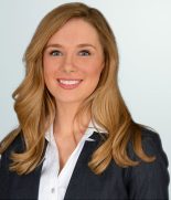 a woman in a business suit smiling for the camera.