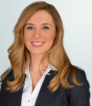 a woman in a business suit smiling for the camera.